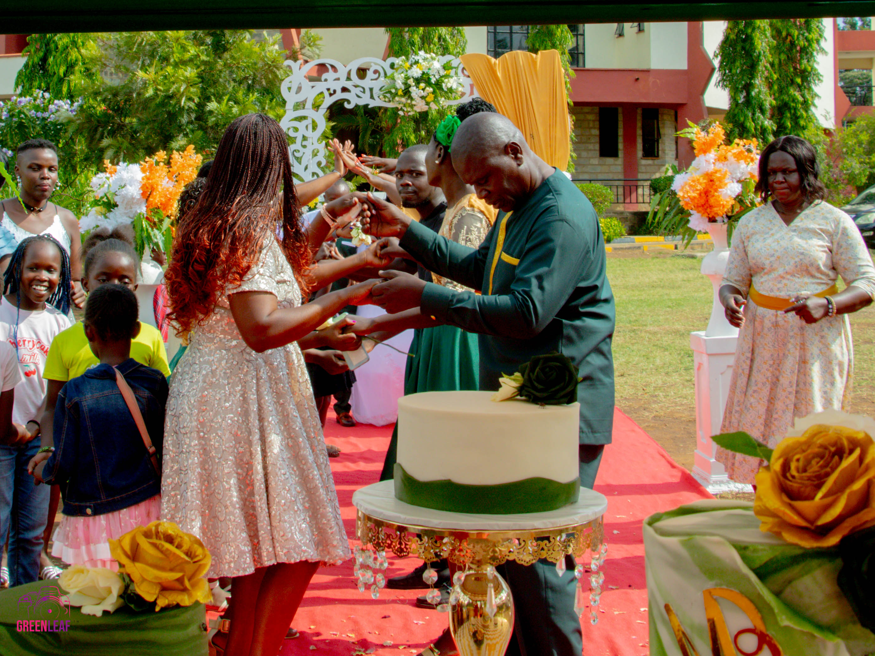 Mercy and Stephen cutting their wedding cake outdoors in Kisumu